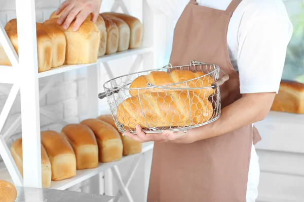 Panadero sosteniendo pan recién horneado en la cocina de la panadería — Foto de Stock