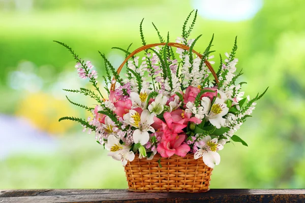 Lindas flores silvestres em cesta de vime no fundo do campo — Fotografia de Stock