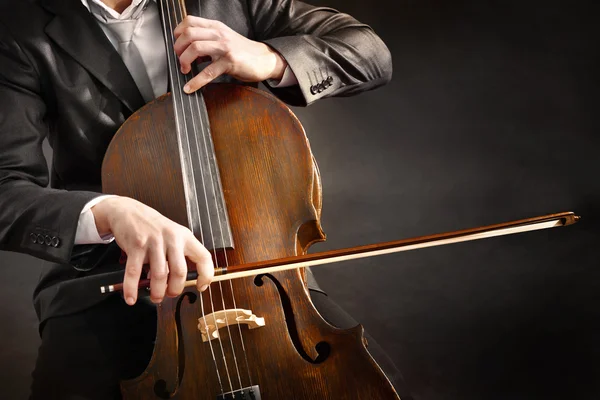 Uomo che suona il violoncello su sfondo scuro — Foto Stock