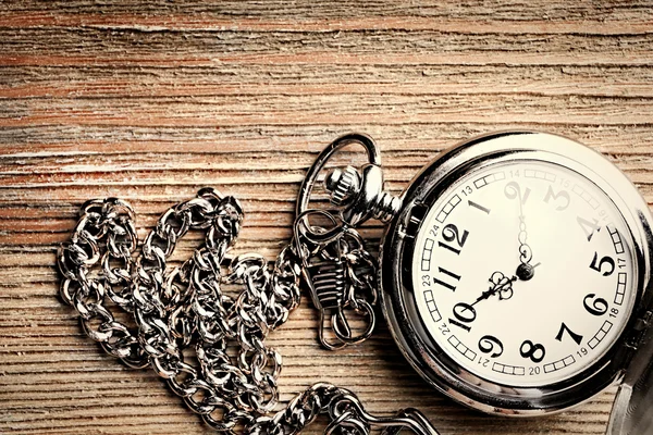 Silver pocket clock on wooden table — Stock Photo, Image