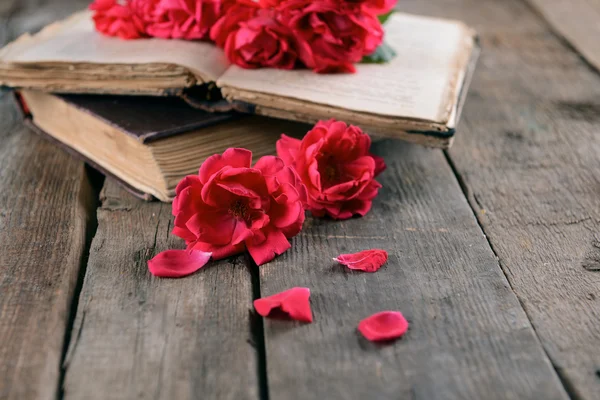 Old books with beautiful flowers on wooden table close up — Stock Photo, Image