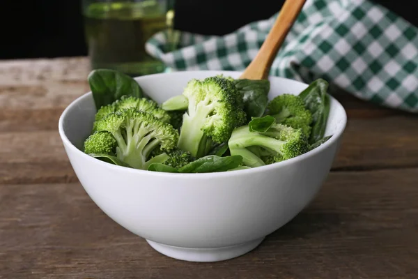 Färsk broccoli med spenat i skål på träbord nära håll — Stockfoto