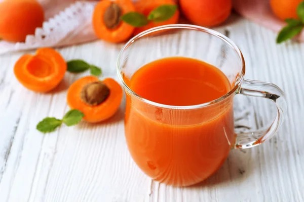 Taza de jugo de albaricoque y frutas frescas en la mesa de cerca — Foto de Stock