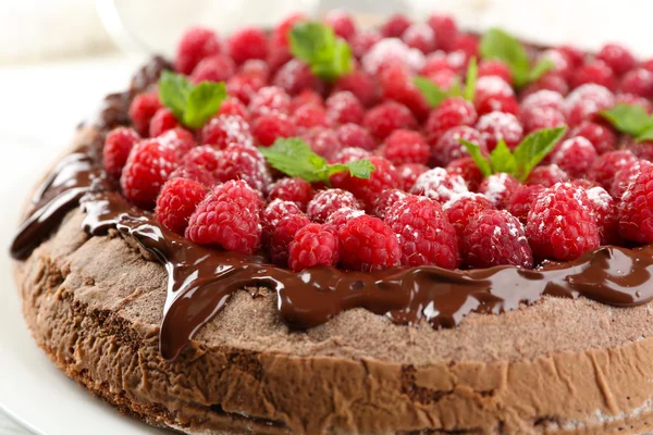 Gâteau avec glaçage au chocolat et framboises sur fond en bois de couleur — Photo