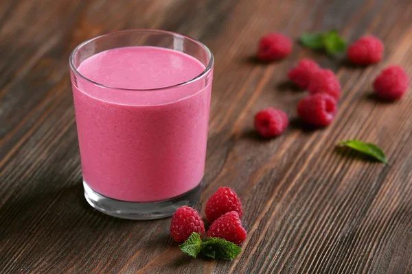 Vaso de batido de leche de frambuesa con bayas sobre fondo de madera —  Fotos de Stock