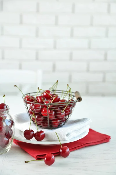 Wiśnie w kosz na stole, na jasnym tle — Zdjęcie stockowe