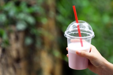 Elinde plastik bardak milkshake tutan bir kadın.