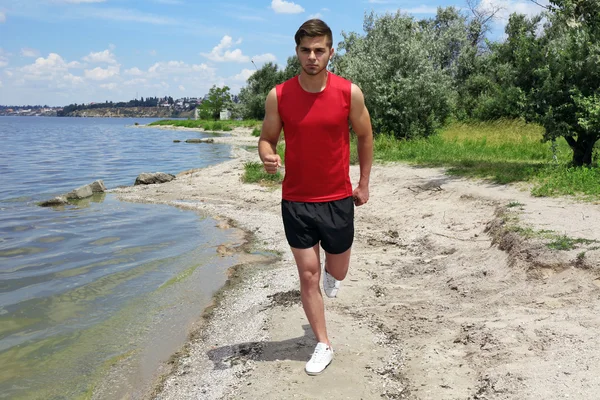 Ung man joggar på stranden — Stockfoto