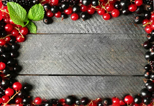 Grosella roja y negra madura sobre fondo de madera —  Fotos de Stock