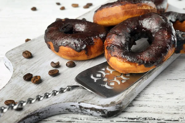 Delicious doughnuts with chocolate icing and coffee beans on table close up — Stock Photo, Image