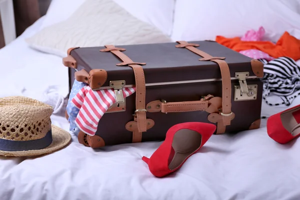 Suitcase with clothing on bed in room — Stock Photo, Image