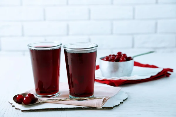 Dvě skleničky s cherry šťáva na stole, na světlé pozadí — Stock fotografie