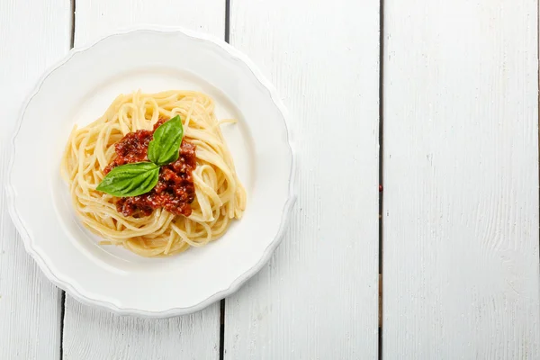 Spaghetti Boloñesa sobre plato blanco, sobre fondo de madera de color — Foto de Stock