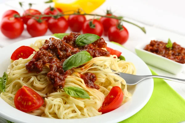 Spaghetti alla bolognese su piatto bianco, su fondo di legno a colori — Foto Stock