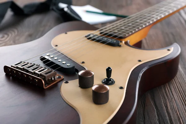 Electric guitar with notebook on wooden table close up — Stock Photo, Image