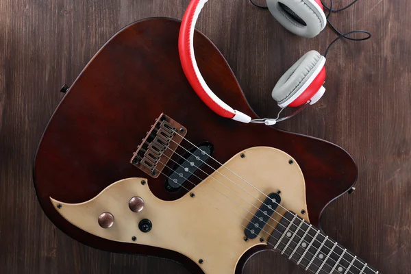 Electric guitar with headphones on wooden table close up — Stock Photo, Image