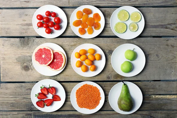 Verschiedene Produkte auf Untertassen auf Holztisch, Draufsicht — Stockfoto