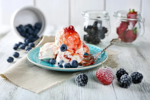 Delicioso sorvete com frutas frescas congeladas e molho, na cor de fundo de madeira — Fotografia de Stock