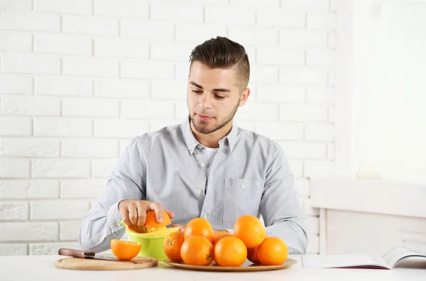 Ung man förbereda apelsinjuice — Stockfoto