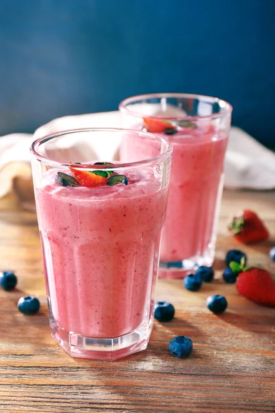 Glasses of berry smoothie on wooden table on dark background — Stock Photo, Image