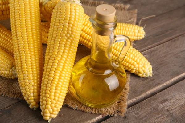 Mais fresco con bottiglia di olio sul tavolo da vicino — Foto Stock