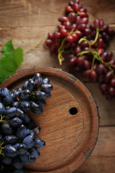 Стара винна бочка і виноград на дерев'яному фоні — стокове фото