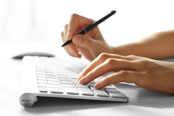 Female hand with pen typing on keyboard — Stock Photo, Image