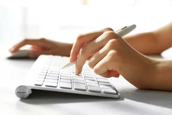 Mão feminina com caneta digitando no teclado — Fotografia de Stock