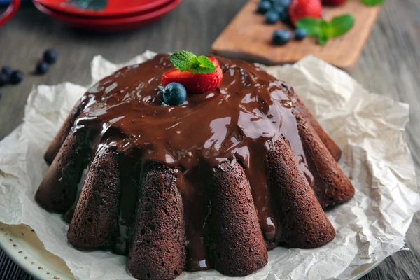 Delicioso bolo de chocolate com bagas em prato na mesa, close-up — Fotografia de Stock