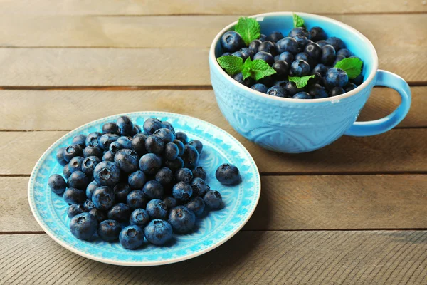 Kop en plaat met verse bosbessen op houten tafel close-up — Stockfoto