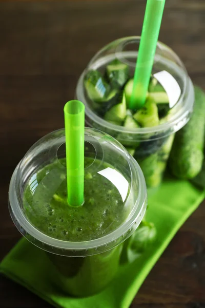 Groene groente- en fruitsector salade en gezonde fresh drink in plastic bekers op houten achtergrond. Kleurrijke dieet concept — Stockfoto
