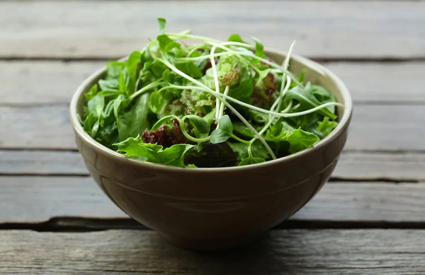 Ahşap masa üzerinde kase taze karışık yeşil salata yakın çekim — Stok fotoğraf