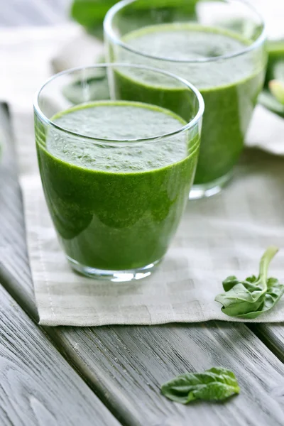 Glasses of spinach juice with napkin on wooden table, closeup — Stock Photo, Image