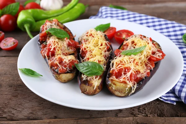 Dish of eggplant with cherry tomatoes and cheese in white plate on wooden table, closeup — Stock Photo, Image