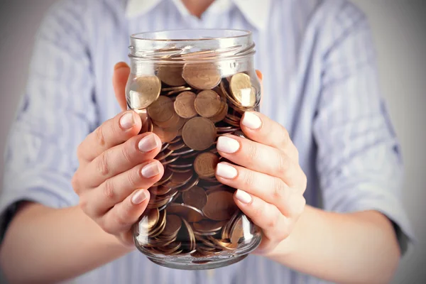 Mujer sosteniendo el frasco de dinero con monedas —  Fotos de Stock