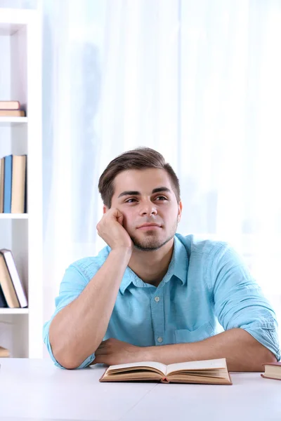 Junger Mann liest Buch am Tisch — Stockfoto