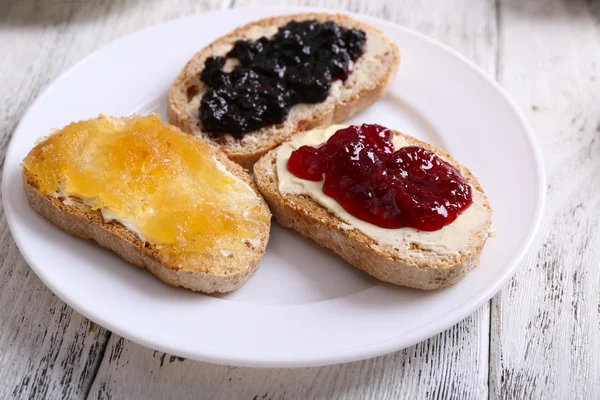 Fresh toast with butter and different jams on table close up — Stock Photo, Image