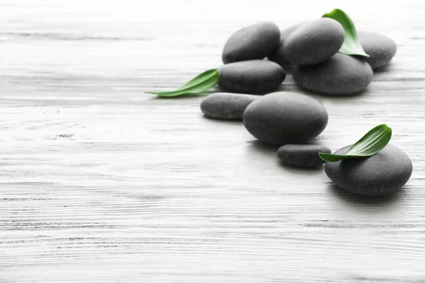 Wellness-Steine mit grünen Blättern auf Holzgrund — Stockfoto