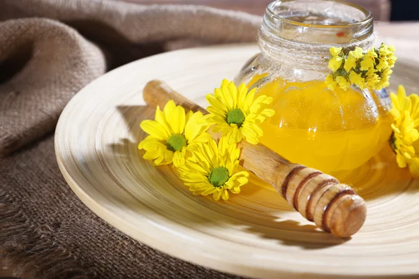 Miele con fiori e tuffatore su vassoio di legno sul tavolo — Foto Stock