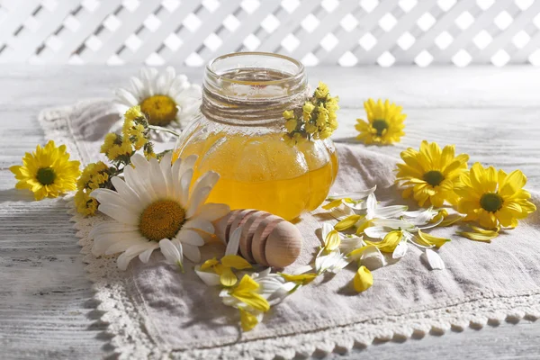 Honey and flowers on napkin on wooden table — Stock Photo, Image