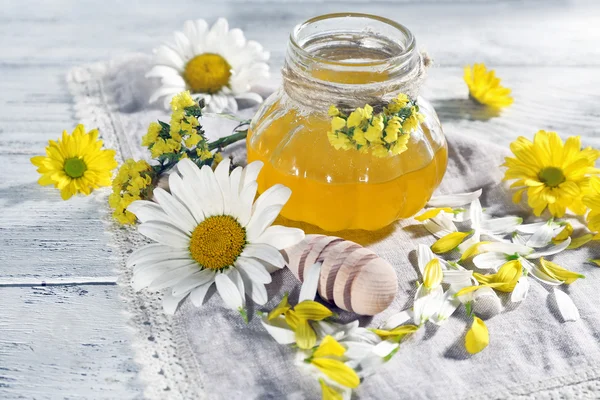 Honey and flowers on napkin on wooden background — Stock Photo, Image