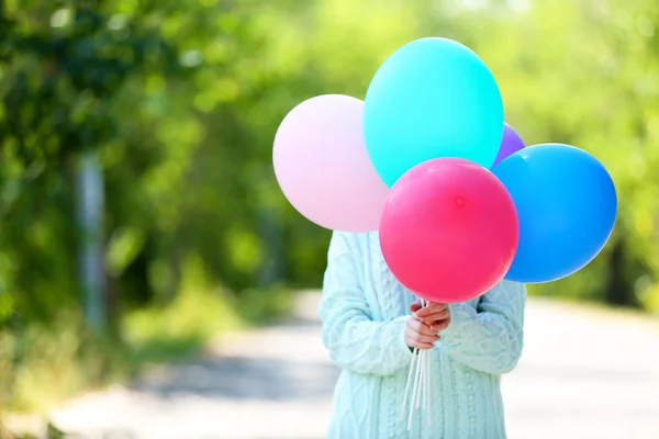 Mädchen hält Luftballons in der Nähe Gesicht — Stockfoto