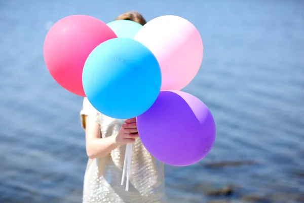 Flicka innehav ballonger nära ansikte — Stockfoto