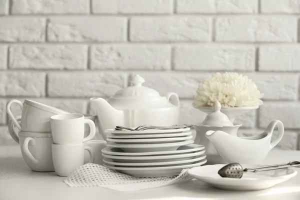 Clean dishes on table on brick wall background — Stock Photo, Image