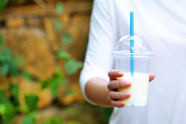 Elinde plastik bardak milkshake tutan bir kadın.