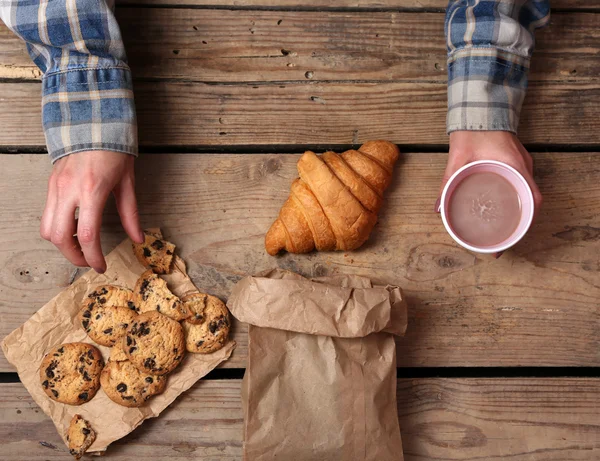 Female hands holding cup of coffee and cookies — Stock Photo, Image