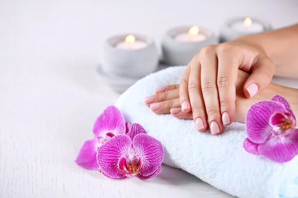 Mãos com manicure francês e flores de orquídea — Fotografia de Stock