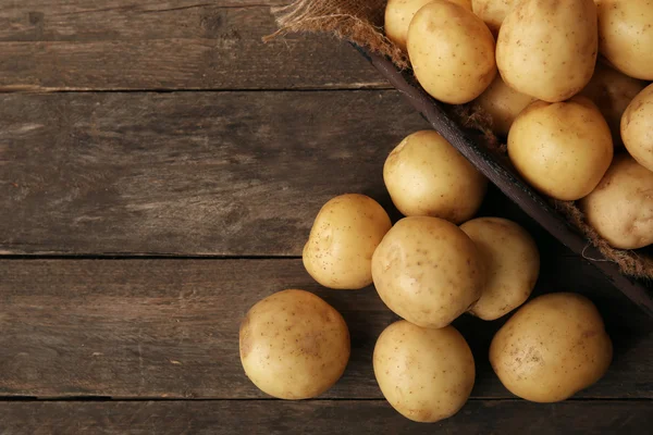 Nieuwe aardappelen in lade op houten tafel — Stockfoto