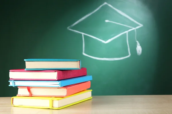 Books and bachelor hat drawing on blackboard background — Stock Photo, Image