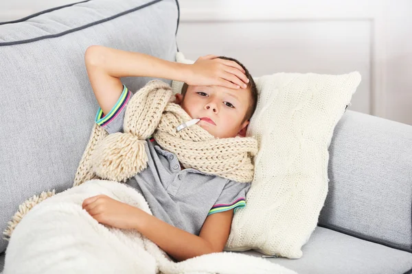 Sjuk pojke med kallt sitter på soffan — Stockfoto